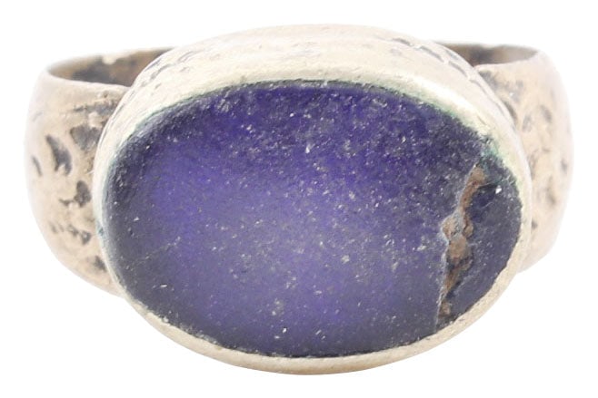 EASTERN EUROPEAN GYPSY RING, 19TH CENTURY, SIZE 8: 19th century. White metal band 4.7mm width flaring to the foliate decorated shoulders. Large oval bezel with cabled bottom and rounded edge and blue “stone” (defective). Attractive with a