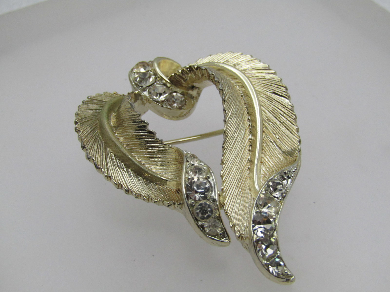 Vintage Gold Leaf Swag Brooch with Rhinestones, Signed Lisner, 1960's-1970's: Vintage Gold Leaf Swag Brooch with Rhinestones, Signed Lisner, 1960's-1970's. It is appx. 2" tall and 1.5" wide. Very good condition. Gold Tone. (W12/22-1/23 SS10079 J LD 3/31/23). Reserve: