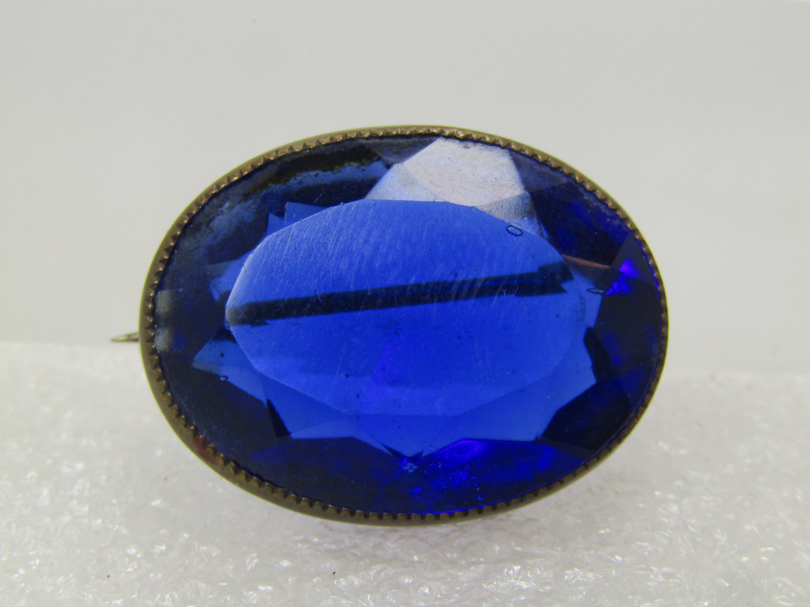 Vintage Brass Blue Glass Brooch, Faceted, 1940's: Vintage Brass Blue Glass Brooch, Faceted, 1940's. This is a royal blue and faceted and is appx. 1" but 5/8". It is oval - the pin extends beyong the frame which could date it a little earlier than