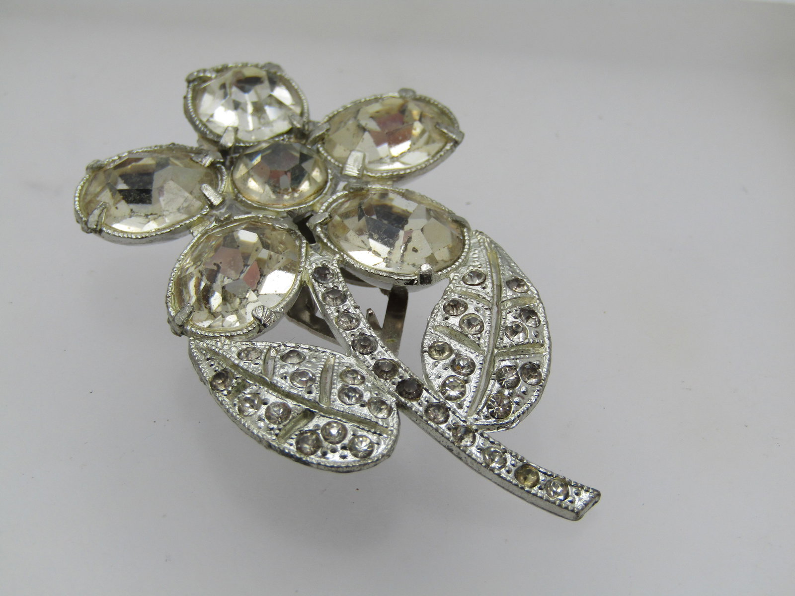 Vintage Pair of Rhinestone Floral Dress Clips, 1940's: Vintage Pair of Rhinestone Floral Dress Clips, 1940's. Silver tone pot metal with a large flower with curved stem and two leaves. It is 2.25" tall and 1.5" wide. Large 12mm by 10mm glass stones as