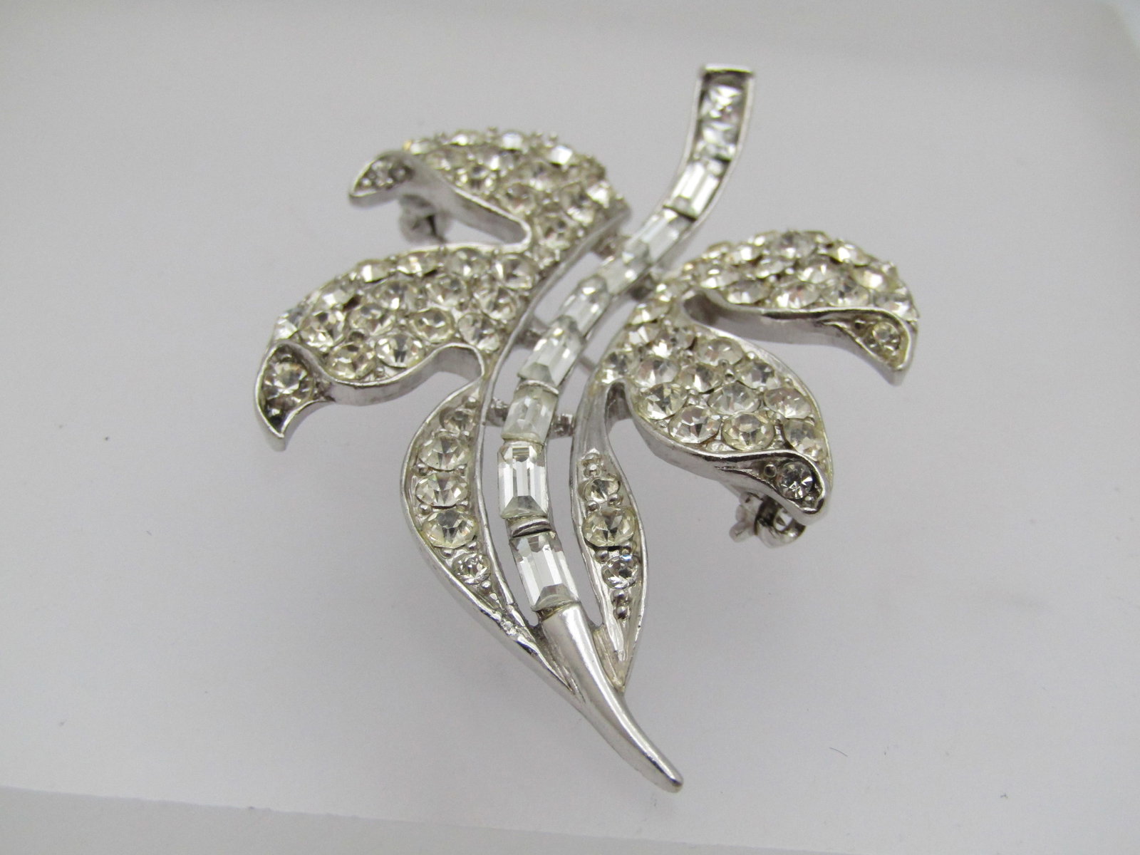 Vintage Rhinestone Leaf Brooch, 1960's 2.25" by 1.5": Vintage Rhinestone Leaf Brooch, 1960's 2.25" by 1.5". Very nicely made with clear rhinestones - baguette stem and pave-set clear round stones throughout the leaf. Smooth silver tone. It is not