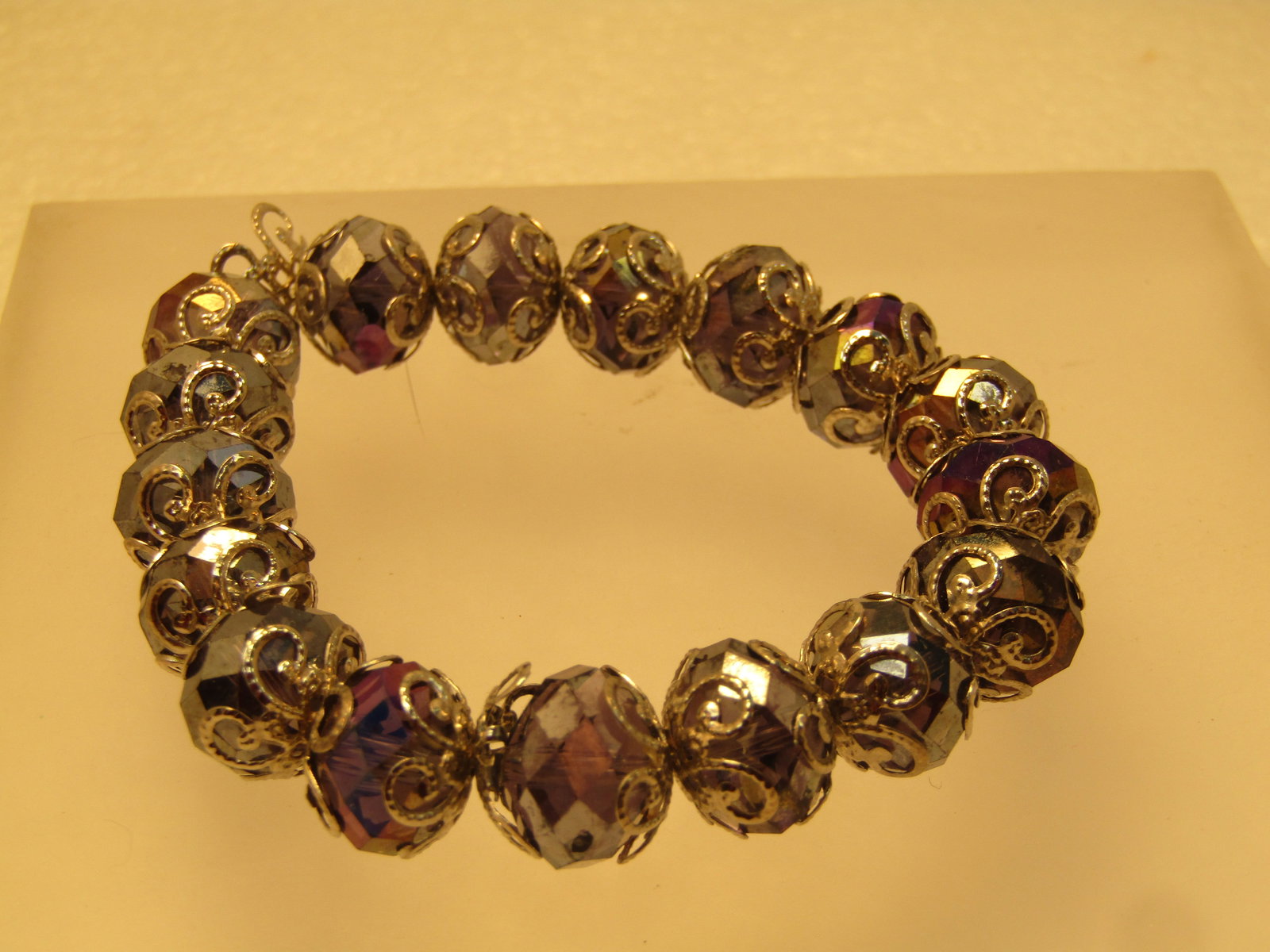 Vintage Purple AB Crystal Beaded Bracelet, Filigree Accents, Stretch, 1980's-1990's: Vintage Purple Aurora Borealis Crystal Beaded Bracelet, Filigree Accents, Stretch, 1980's-1990's. The beads are appx. 11.5mm wide and have a silver tone filigree endcap on each side of the bead. At re