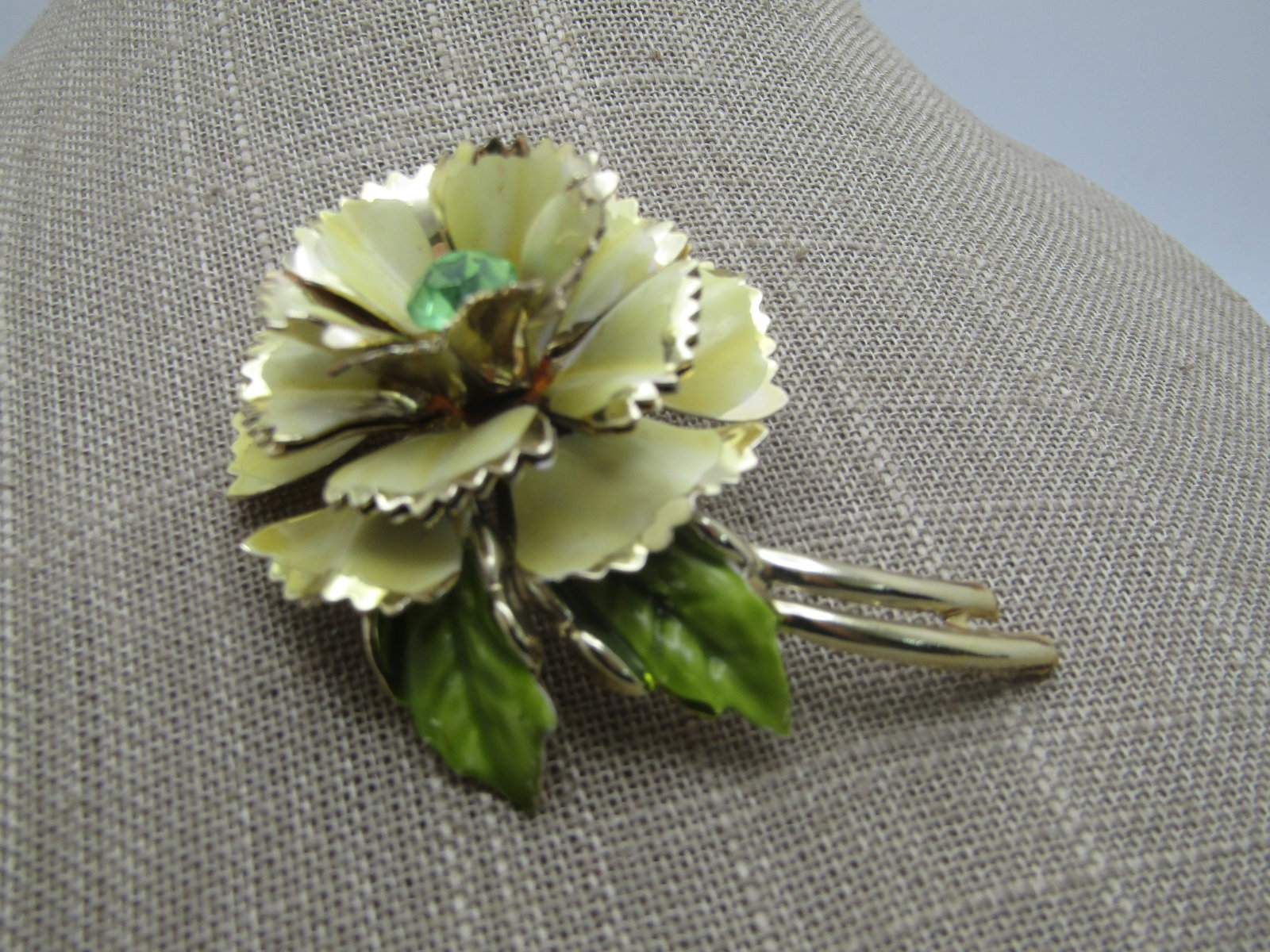 Vintage Enameled Rhinestone Floral Stem Brooch, 1950's-1960's: Vintage Enameled Rhinestone Floral Stem Brooch, 1950's-1960's. It has three tiers of yellow enameled petals with pointed edges. Green enameled leaves and a double curved stem. 8mm green rhinestone
