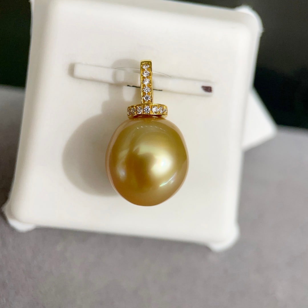 18K gold South Sea pearl pendant: Title: 18K gold South Sea pearl pendant Description: This pendant showcases a lustrous South Sea golden pearl, renowned for its fine luster and nearly round shape. The pearl has a smooth surface with
