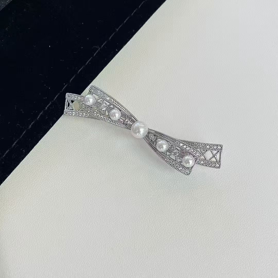 Pearl brooch: Title: Pearl brooch Description: This brooch features a delicate butterfly bow design, set with natural freshwater round pearls. The extremely bright high-quality pearls add nobility and elegance to