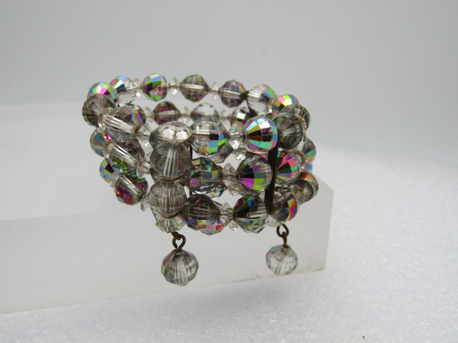 Vintage Aurora Borealis Coiled Bracelet, 6.5"-7.5", 1960's: Vintage Aurora Borealis Coiled Bracelet, 6.5"-7.5", 1960's. Triple strand of crystal faceted beads with a clear and purple hue with the A.B. shimmer. It is appx. 7/8" wide and has a danglig bead on th