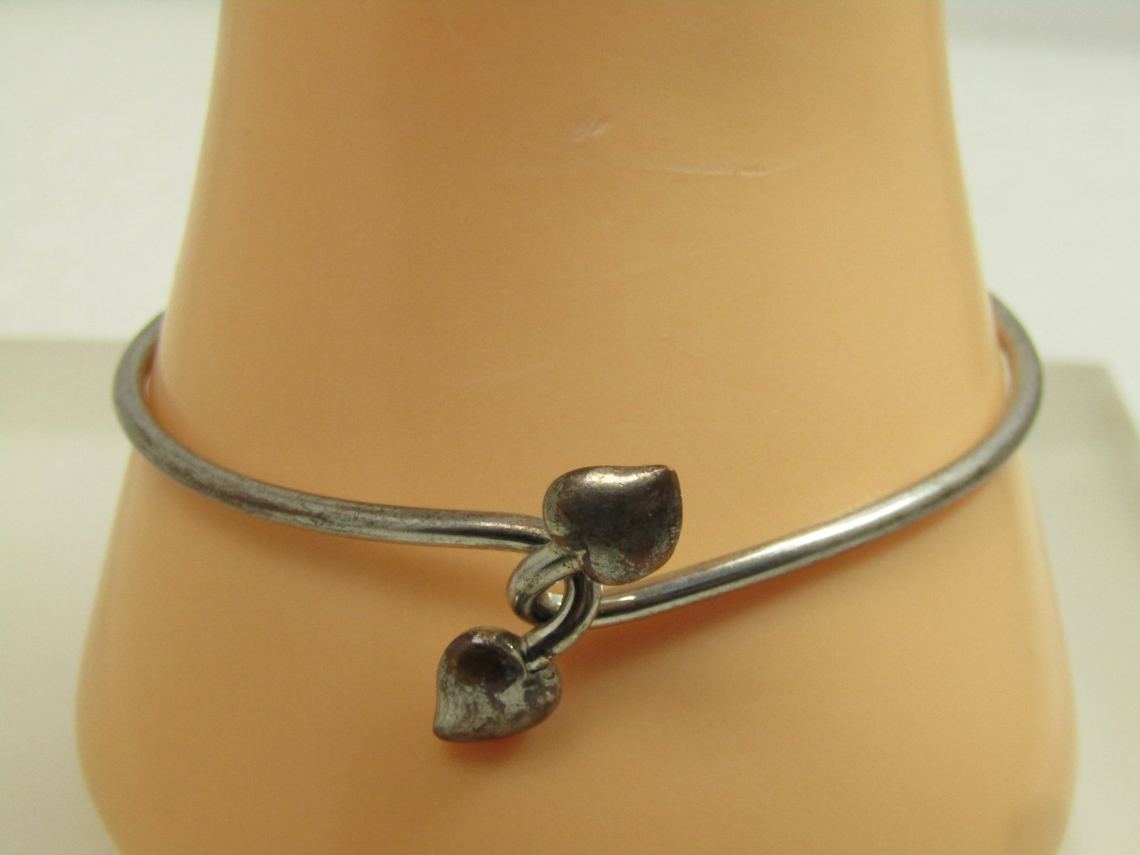 Vintage Inlocking Heart Bangle Bracelet, 7.5", 1970's-1980's: Vintage Inlocking Heart Bangle Bracelet, 7.5", 1970's-1980's. Silver tone wire bangle bracelet that has a hook lock on top with a heart on each side. It is not marked or signed. There is some finish w