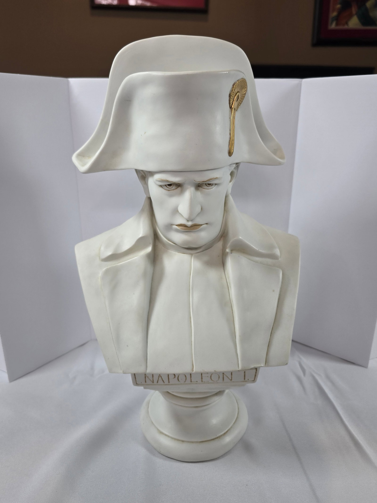 Grand Tour Style Neoclassical Bust of Napoleon I: A finely detailed bust of Napoleon I, rendered in white bisque porcelain and accented with gilt details. The bust depicts Napoleon in his iconic bicorne hat with a gilded imperial eagle insignia, and