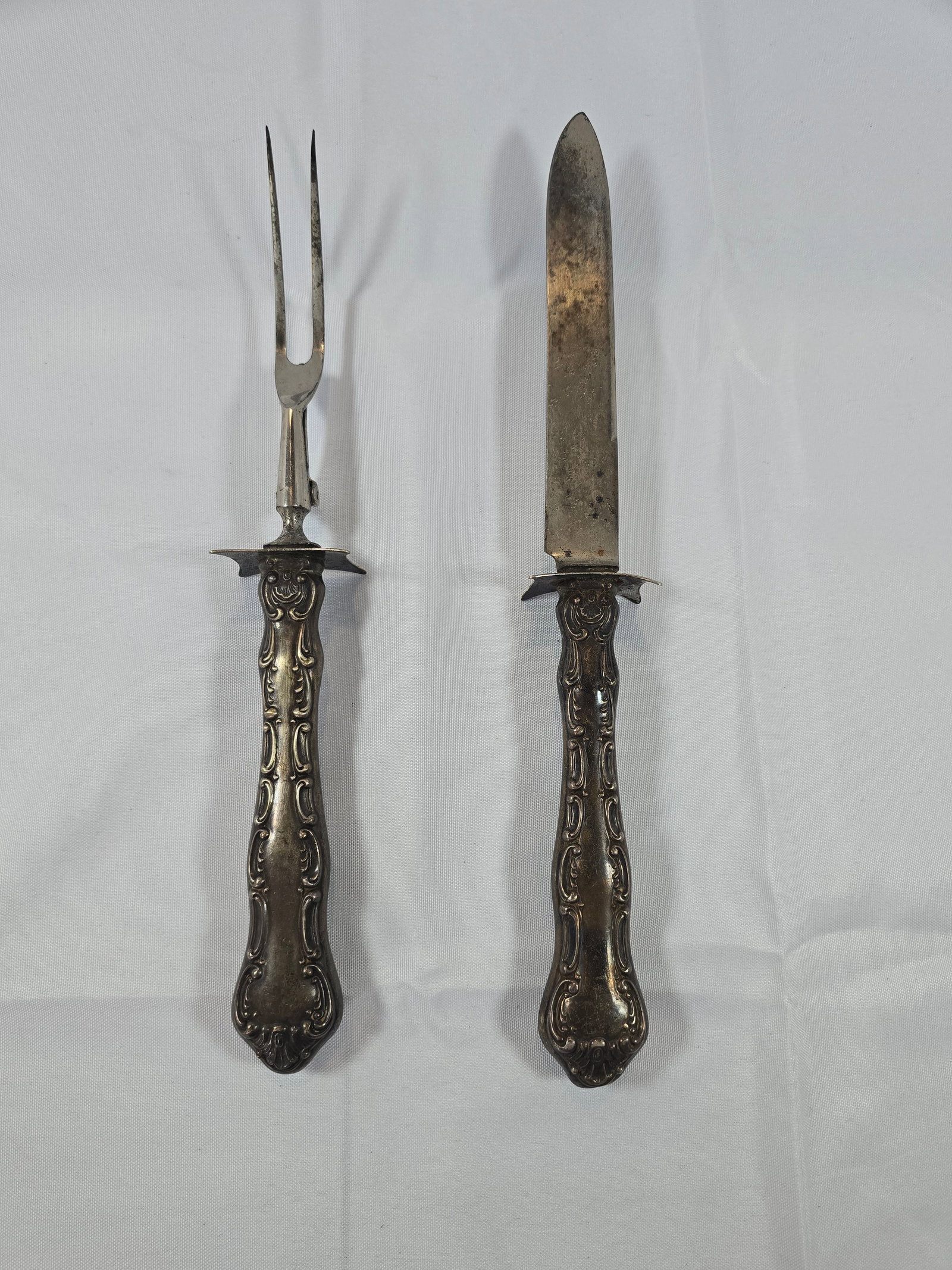 Antique Silver Ornate Carving Set: This exquisite antique carving set, likely dating from the late 19th to early 20th century, embodies the Rococo Revival style with its elaborate scrollwork and shell motifs. The set comprises a