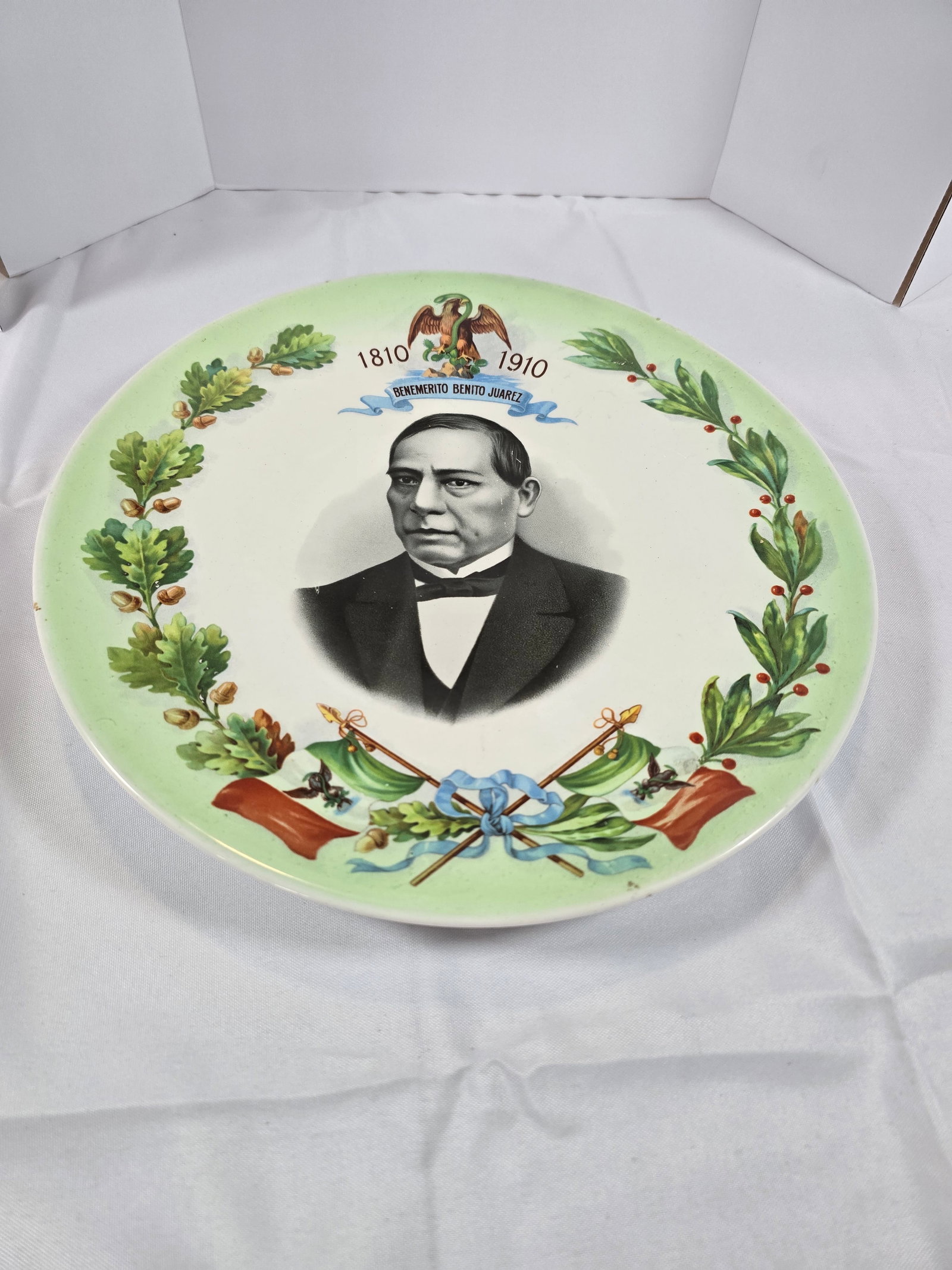 Benito Juárez Centennial Commemorative Plate: A commemorative porcelain plate celebrating the centennial of Benito Juárez's birth (1810-1910). The plate features a central black and white portrait of Benito Juárez, surrounded by a border of