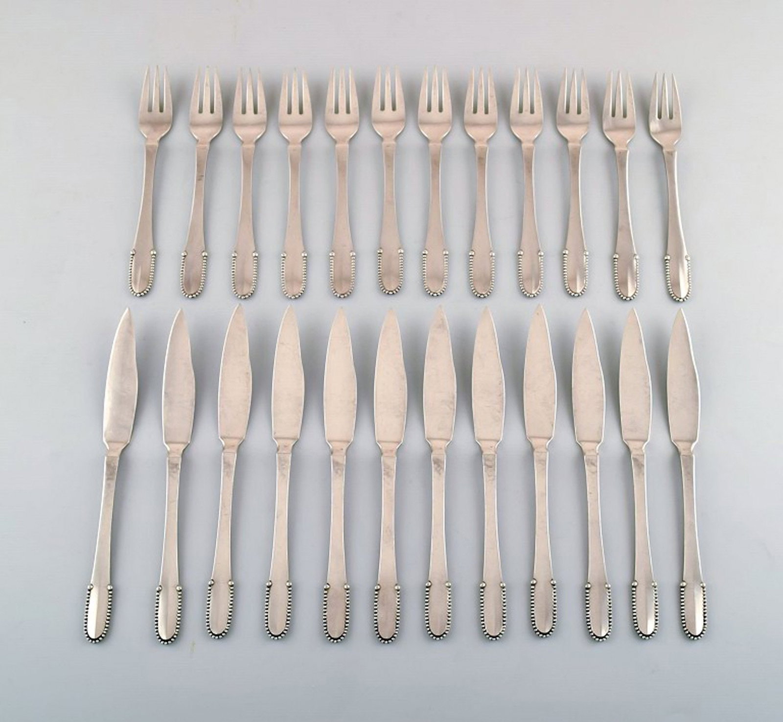Georg Jensen Beaded complete 12 persons fish service.: Title:Georg Jensen Beaded complete 12 persons fish service. Description:Georg Jensen Beaded complete 12 persons fish service. 12 fish knives, 12 fish forks. Measures: knife 20.5 cm. Stamped. In perfec