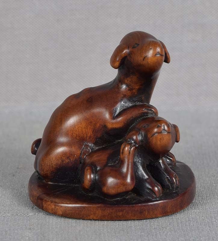 Early 19c netsuke DOG & PUPPY: Early 19th century boxwood netsuke of a dog seated next to its puppy, who is scratching its ear with int hind paw. Wonderfully captured mood of the scene, superb realistic carving of their muscle and