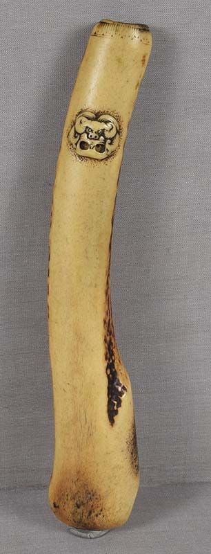 19c Japanese ASAKUSA KISERUZUTSU Japanese pipe case SHISHI MASK: 19th century Japanese Asakusa school staghorn kiseruzutsu - tobacco pipe case - of elegant simple shape with relief carving of a shishi mask. Eyes are inlaid with metal, channel for hanging goes throu