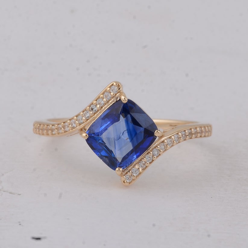 1.65 Ct Cushion Sapphire 9K Gold Ring: 1.65 Total Carat Sapphire 9K Gold Ring Specifications Total Weight 1.878 g Center Gemstone Sapphire Gemstone Carat Weight 1.52 Carats Gemstone Measurements 7.10X6.30X3.30 mm Additional Gemstones White