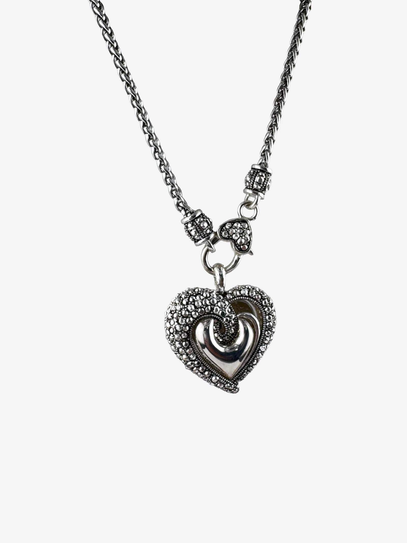 Sterling Silver and Marcasite Heart Pendant Necklace: Vintage sterling silver necklace featuring a heart-shaped pendant adorned with pave-set marcasite stones. The central design of the heart showcases a polished silver intertwined motif, giving the
