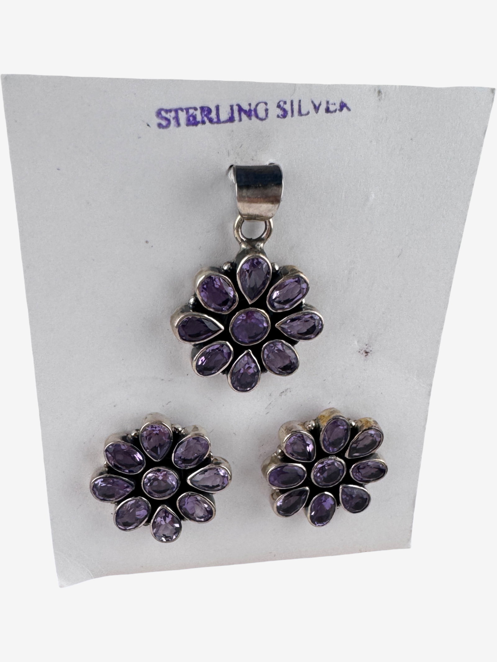 Vintage Sterling Silver Jewelry Set: A charming sterling silver jewelry set featuring a pendant and a pair of stud earrings, both designed in a floral motif. Each piece is adorned with marquise-cut possibly amethyst gemstones, arranged t