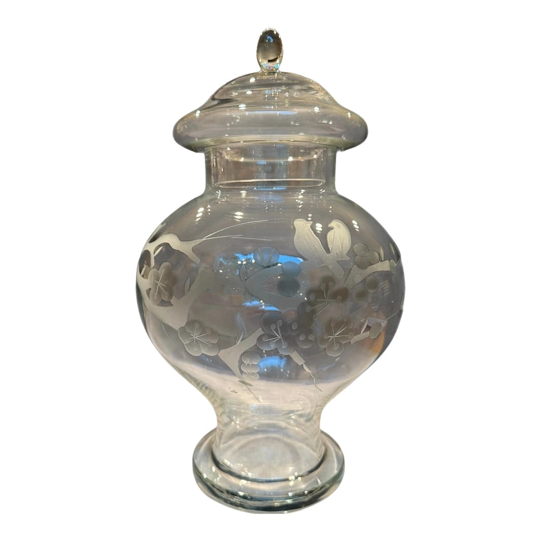 1950s Glass Ginger Jar With Etched Cherry Blossom Birds Motif: Offered is a gorgeous chinosserie-style 1950s clear glass ginger jar. This exquisite piece details an etched ornate scene of a pair of birds perching on a cherry blossom branch. Removable lid. 