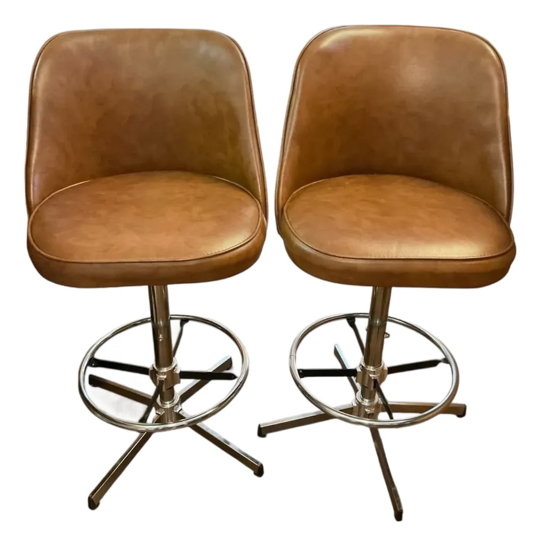 1970s Vintage Chrome and Cognac Vinyl Swivel Bar Stools - A Pair: A fantastic pair of vintage 1970s swivel bar stools featuring warm cognac vinyl upholstery and gleaming chrome pedestal bases. These retro beauties have curved bucket seats with padded backrests for