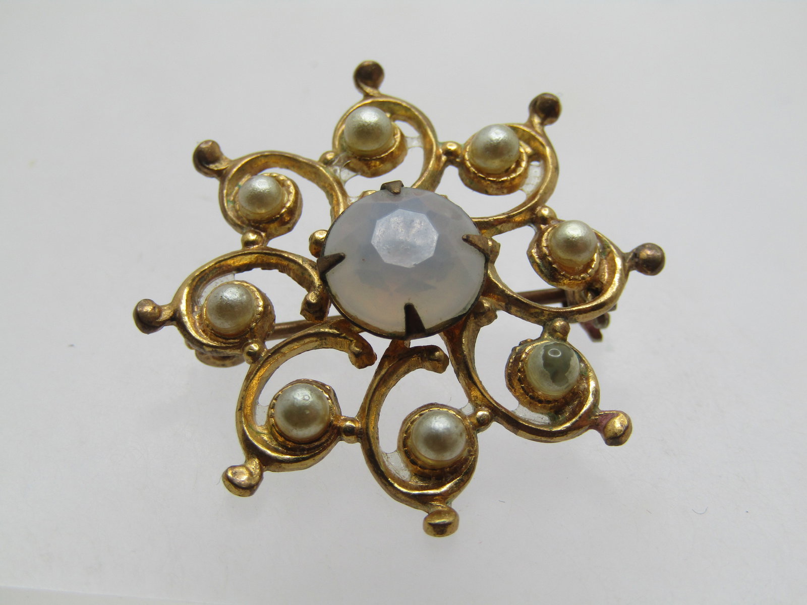 Vintage Faux Pearl Brooch/White Rhinestone Star/Blossom Shaped, 1940's-1950's: Vintage Faux Pearl Brooch/White Rhinestone Star/Blossom Shaped, 1940's-1950's. It has a raised faceted prong-set opally white glass stone that is appx. 8.5mm. Around that are curved spiral sections th