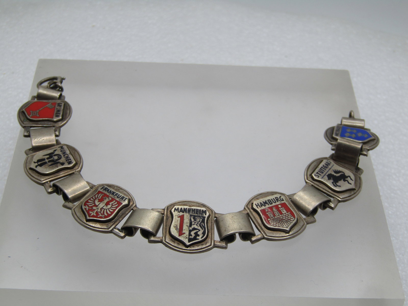 Vintage Sterling German Tourist Charm Bracelet, 7.75", 1940's-1950's: Vintage Sterling German Charm Tourist Bracelet, 7.75", 1940's-1950's. There are seven enameled shield-shaped chams mounted on a wider and curved base. The charms are: Bremen; Munchen; Frankfurt;