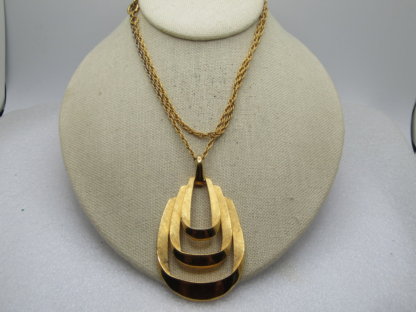 Vintage Crown Trifari Looped Pendant Necklace, 28", 1960's-1970's: Vintage Crown Trifari Looped Pendant Necklace, 28", 1960's-1970's. Gold tone with textured and smooth finish on the triple staggeredlooped pendant with smooth bail. The pendant is appx. 3" by