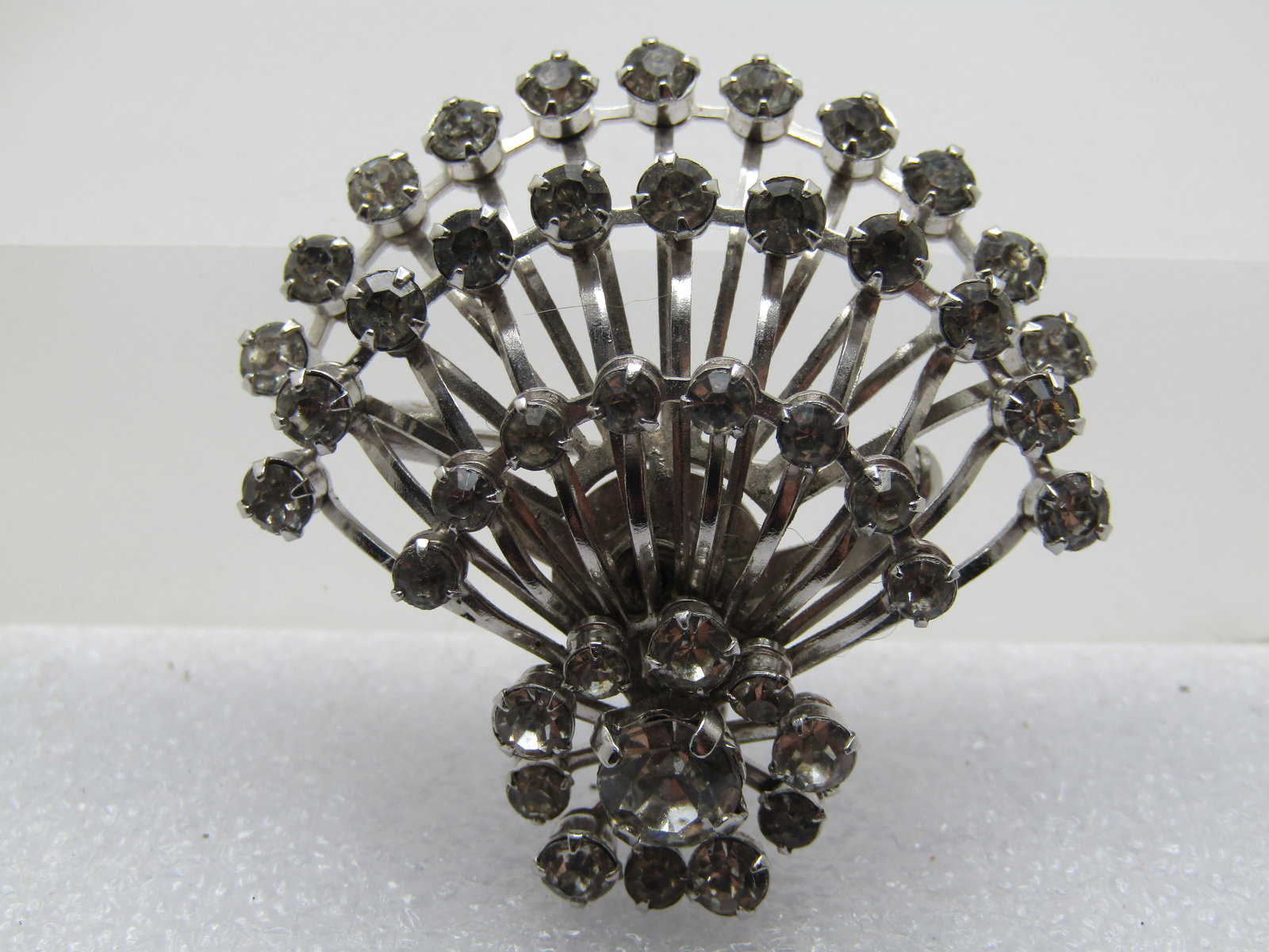 Vintage Clear Rhinestone Cluster Brooch/Pendant, Curved Rays, 1960's: Vintage Clear Rhinestone Cluster Brooch/Pendant, Curved Rays, 1960's. Silver tone with a blossom cluster at one end and three rows coming out from that that are curved and appx. one-third around the b