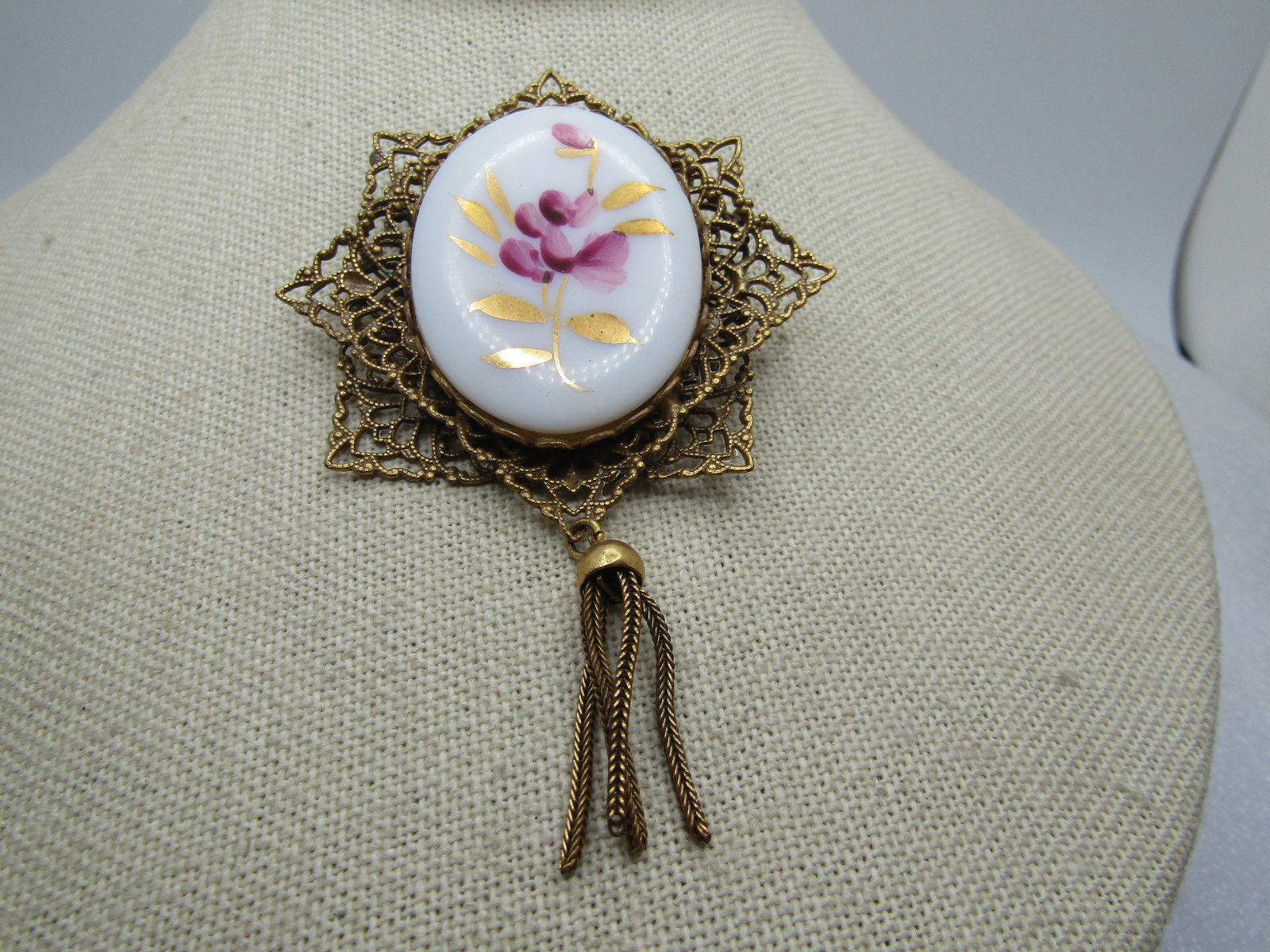 Vintage Filigree Floral Cameo Brooch, with Tassel 1940's-1960's: Vintage Filigree Floral Cameo Brooch, with Tassel 1940's-1960's. This is appx. 3.75" long and 2.5" wide. It has a 1.75" red and gold leaf painted floral design on the cameo piece that is bezel-set in
