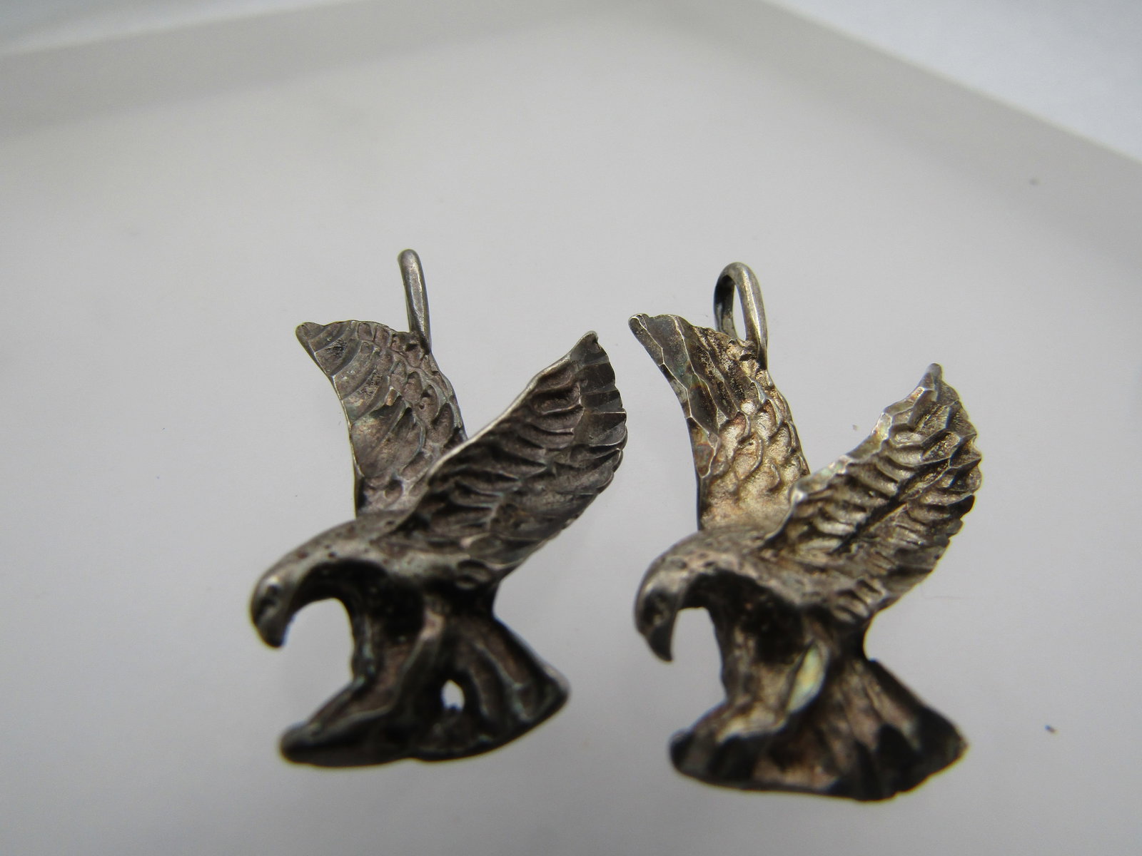 Vintage Pair Sterling Eagle Pendants, Signed LLE, 1980's-1990's: Vintage Pair Sterling Eagle Pendants, Signed LLE, 1980's-1990's. 1-1/8" tall and 7/8" wide. Diamond cut accents on the wings. The one bail is a solid bail and the other is not soldered at the top