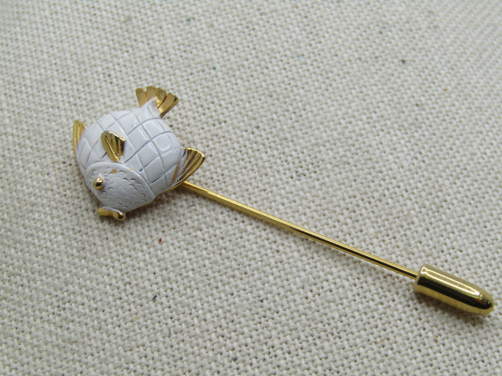 Vintage White Enameled Fish Stick Pin, 1960's-1970's: Vintage White Enameled Fish Stick Pin, 1960's-1970's, with safety cap. Gold tone extured fins and tail and lips and eye with a white enameled body with lined details. The fish is appx. 3/4" tall and