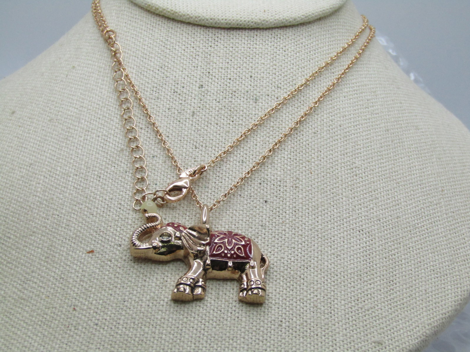 Rose Tone Enameled Elephant Necklace, 30", signed.: Rose Tone Enameled Elephant Necklace, 30". red enameled saddle blanket on the rose gold tone elepahnt with a 30" chain, including the extender chain with NWT hang tag. The elephant also has a red enam