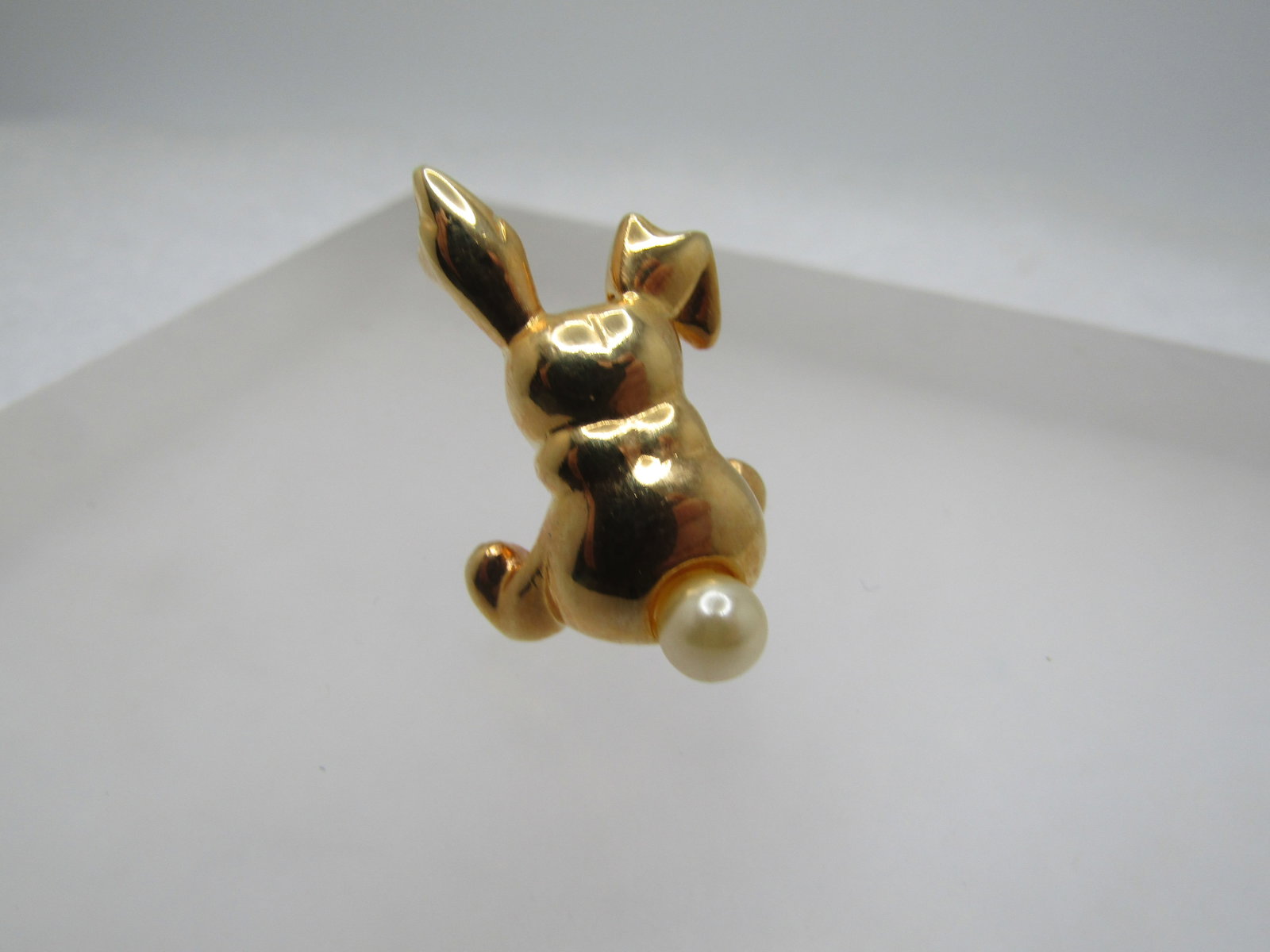 Vintage Bunny Brooch with Faux Pearl Tail, 1970's-1980's: Vintage Bunny Brooch with Faux Pearl Tail, 1970's-1980's. Gold tone bunny - looking at him frm his back. One ear is bend down. It is appx. 1" tall and 3/4" wide. heavy smooth gold tone metal. 