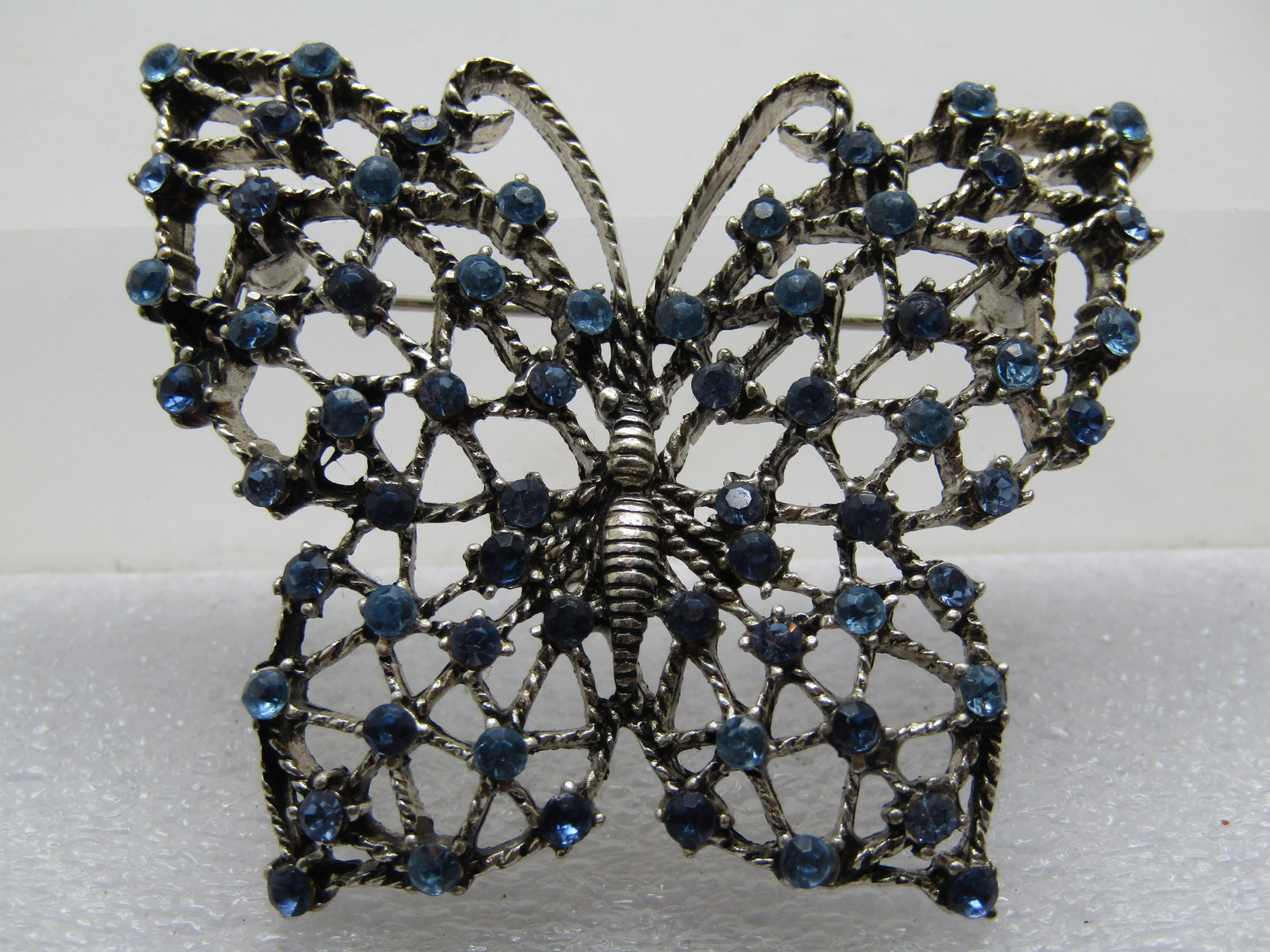 Vintage Monet Blue Butterfly Rhinestone Brooch, 1960's-1970's: Vintage Monet Blue Butterfly Rhinestone Brooch, 1960's-1970's. It is appx. 2" wide and 1-7/8" tall with light and darker blue rhienstones and open work throughout the wings. Silver tone. All