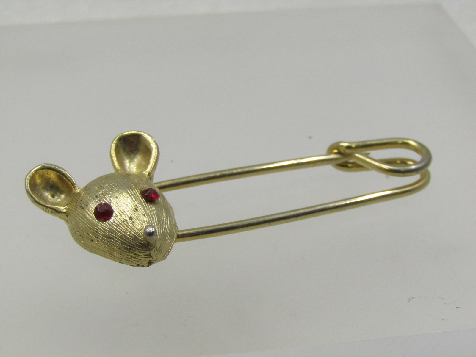 Vintage Mouse Safety Pin Brooch, Rhinestone Eyes, 1960's: Vintage Mouse Safety Pin Brooch, Rhinestone Eyes, 1960's. It is gold tone with a textured 1" tall and 3/4" wide mouse head with rounded ears, red rhinestone eyes and a gold bead nose on one end of a s