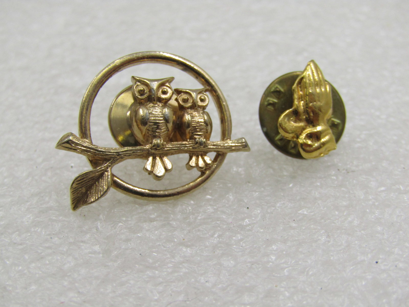 Vntage Avon Owl Tack Pin & Praying Hands Tack Pin: Vntage Avon Owl Tack Pin & Praying Hands Tack Pin. Avon's Two owls sitting on a branch with a single leaf with a circle frame tack pin. Appx. 1970's-1980's. Gold tone and in very good condition. It