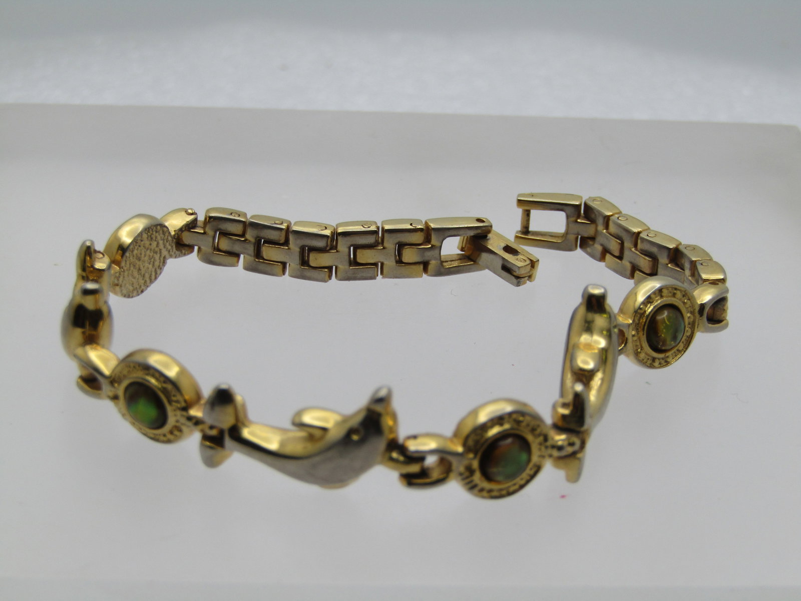Vintage Dolphin Faux Opal Bracelet, 7.5", 1980's: Vintage Dolphin Faux Opal Bracelet, 7.5", 1980's. Flip clasp, gold tone with round links with a faux opal setin the center and three dolphnis across the top of the wrist with a mesh link at the