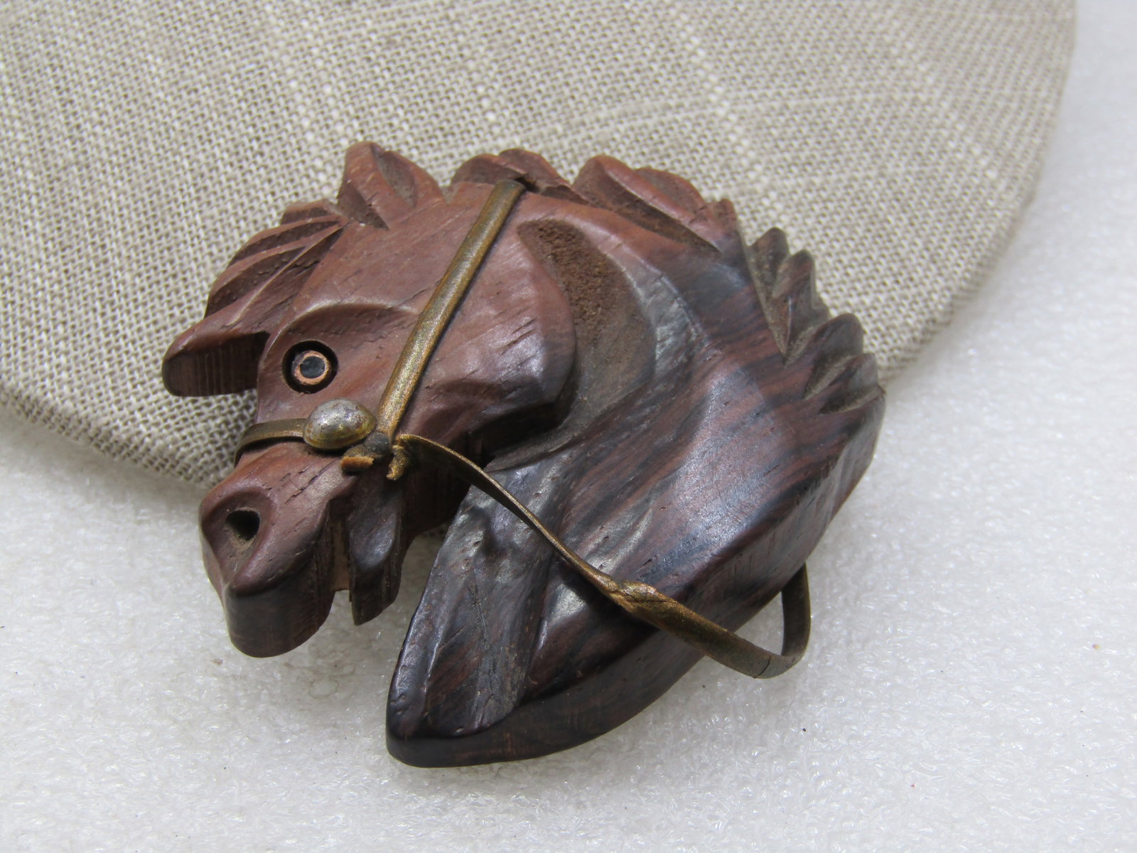 Vintage Carved Wooden Horsehead Brooch, 1940's: Vintage Carved Wooden Horsehead Brooch, 1940's. Dark wooden with nice grain and gold tone plAstic bridal and reins and appx. 2.5" tall and wide. Very nice carved detail. Not signed by the maker. Very