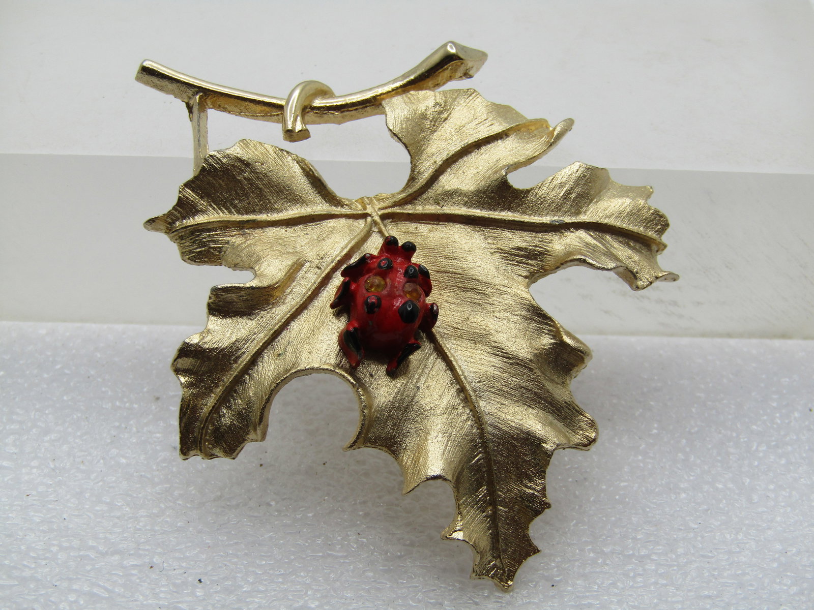 Vintage Lady Bug on Leaf Brooch, Sarah Coventry, 1960's-1970's: Vintage Lady Bug on Leaf Brooch, Sarah Coventry, 1960's-1970's. The leaf is a satiny finish with details and a red with a red and black enameled lady but sitting on the leaf with two rhinestones on th
