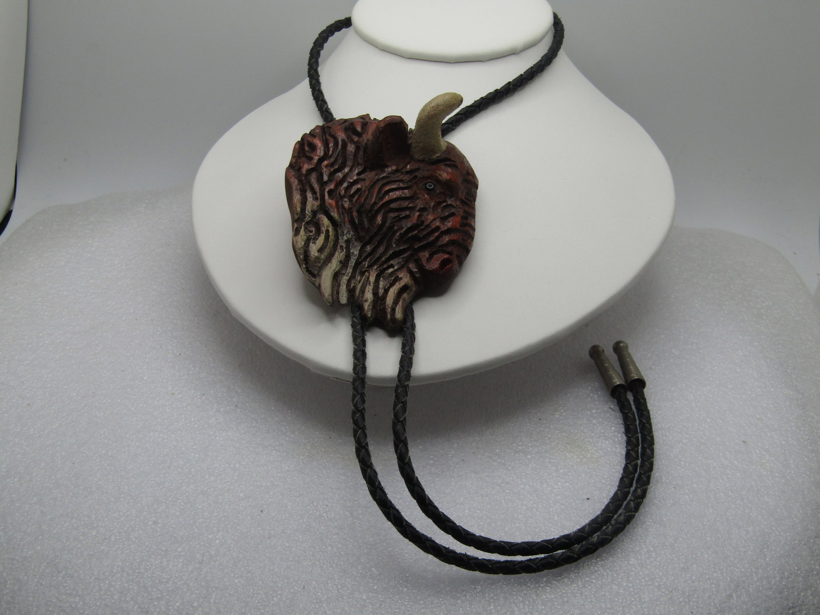 Vintage Carved Buffalo Bolo Tie, 36", Mid-Century, Southwestern: Vintage Carved Buffalo Bolo Tie, 36", Mid-Century. Larged wooden carved buffalo with painted accents and coloring. Glass eye. Braided black leather tie with silver tone end caps. The buffalo is