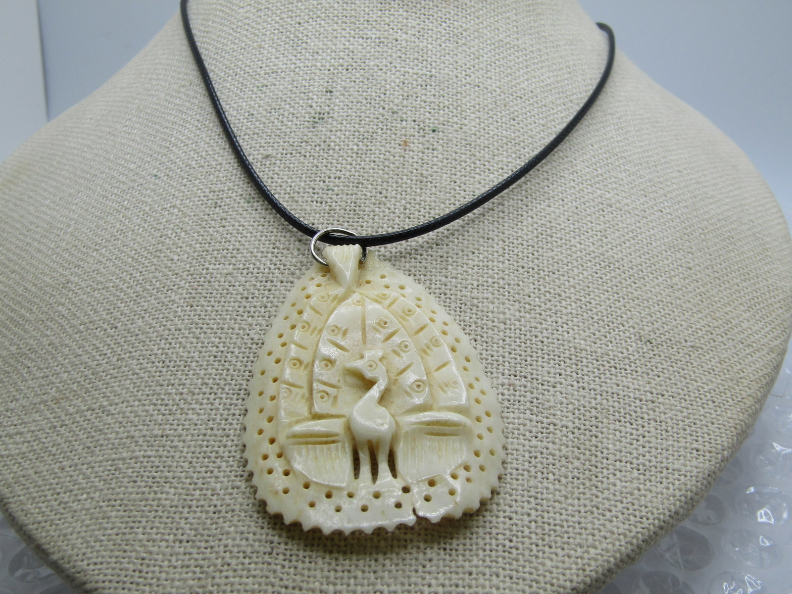 Vintage Carved Peacock Necklace, 20" Black Cord: Vintage Carved Peacock Necklace, 20" Black Cord. This is a white carved teired peacock pendant with little holes carved through the piece in two rows around the outer endge. Carved into a natural