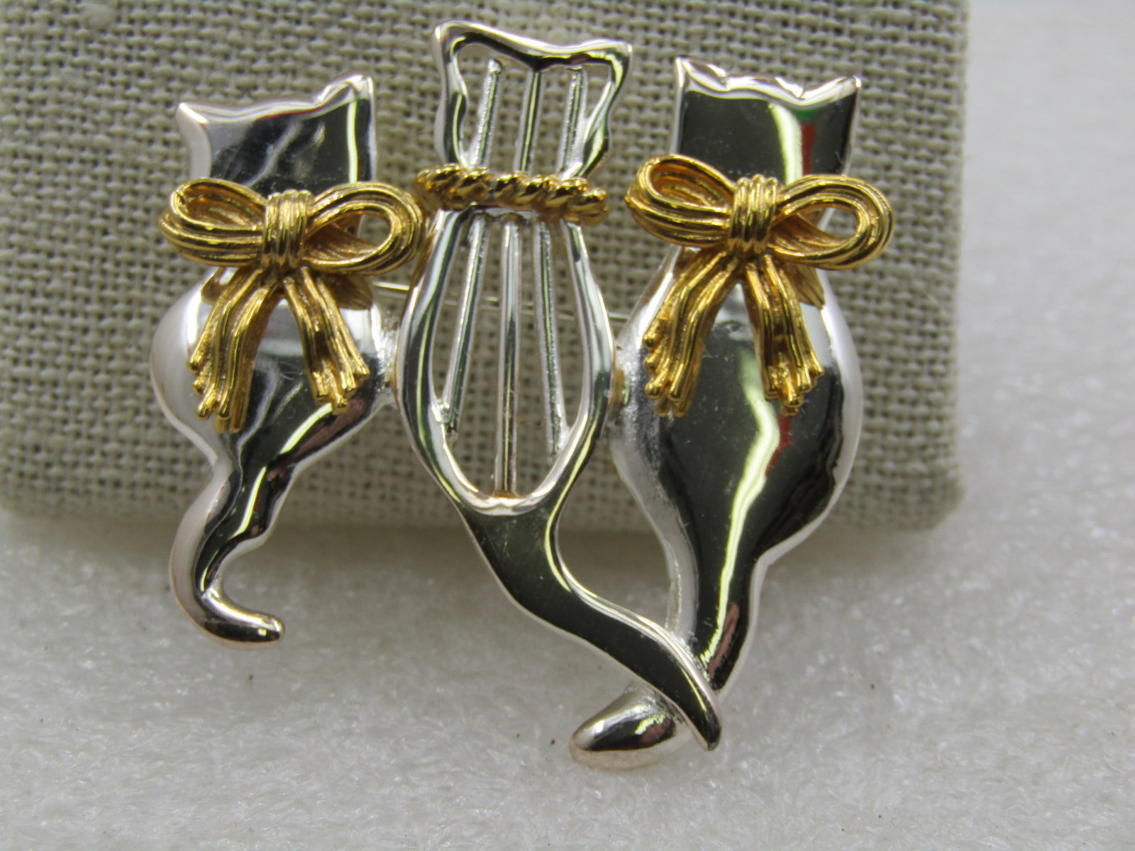 Vintage Two-Tone Three Cats Brooch, 1.75": Vintage Two-Tone Three Cats Brooch, 1.75" tall and wide. Silver tone cats, three of them, sitting side-by-side, view from behind. A smaller one on the left and a larger on the right, each with a gold