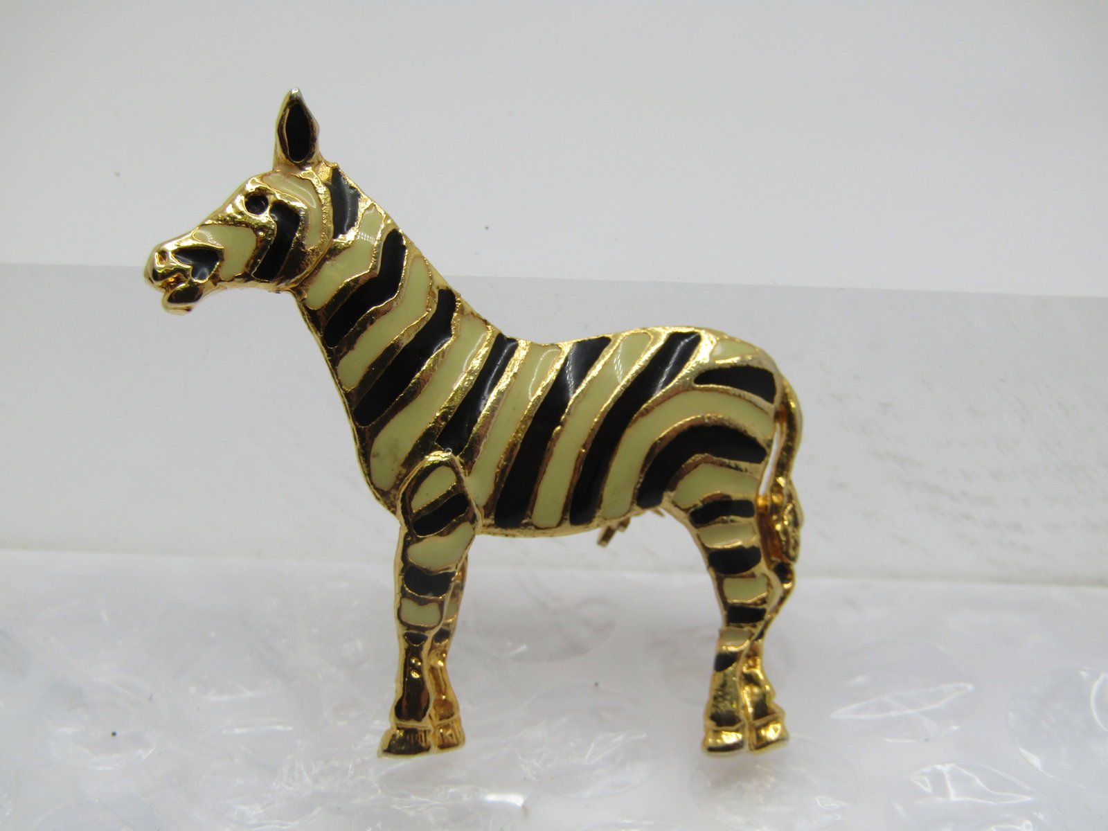 Vintage Enameled Zebra Brooch, 2": Vintage Enameled Zebra Brooch, 2" wide and 1.75" tall. Enameled in black and a very pale yellow/white. Gold tone. It is not signed or marked. Very good condition Age is appx. 1980's-1990's. (W111922.5