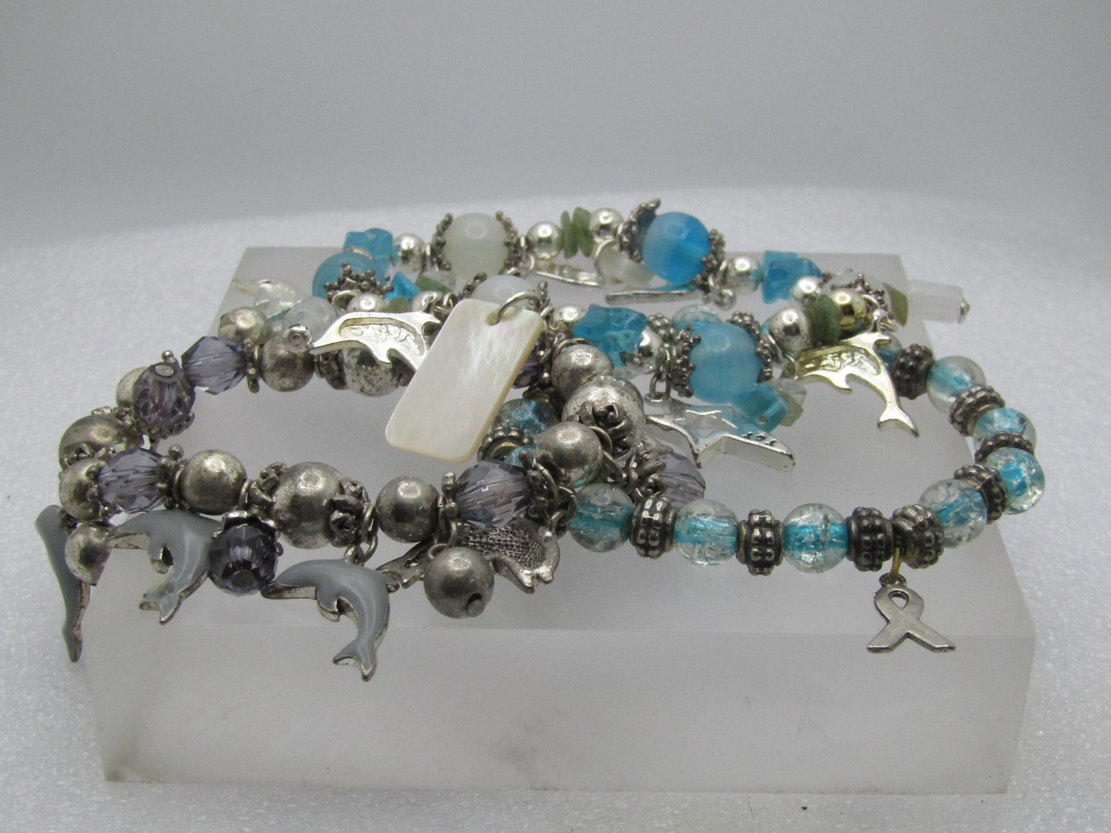 2 Dolphin Stretch Bracelets, Glass Beaded and 1 Support Bracelet: 2 Dolphin Stretch Bracelets, Glass Beaded and 1 Support Bracelet. One dolphin bracelet has aqua beads and mother of pearl and glass bead with some pale green nuggets. There is an open shooting star