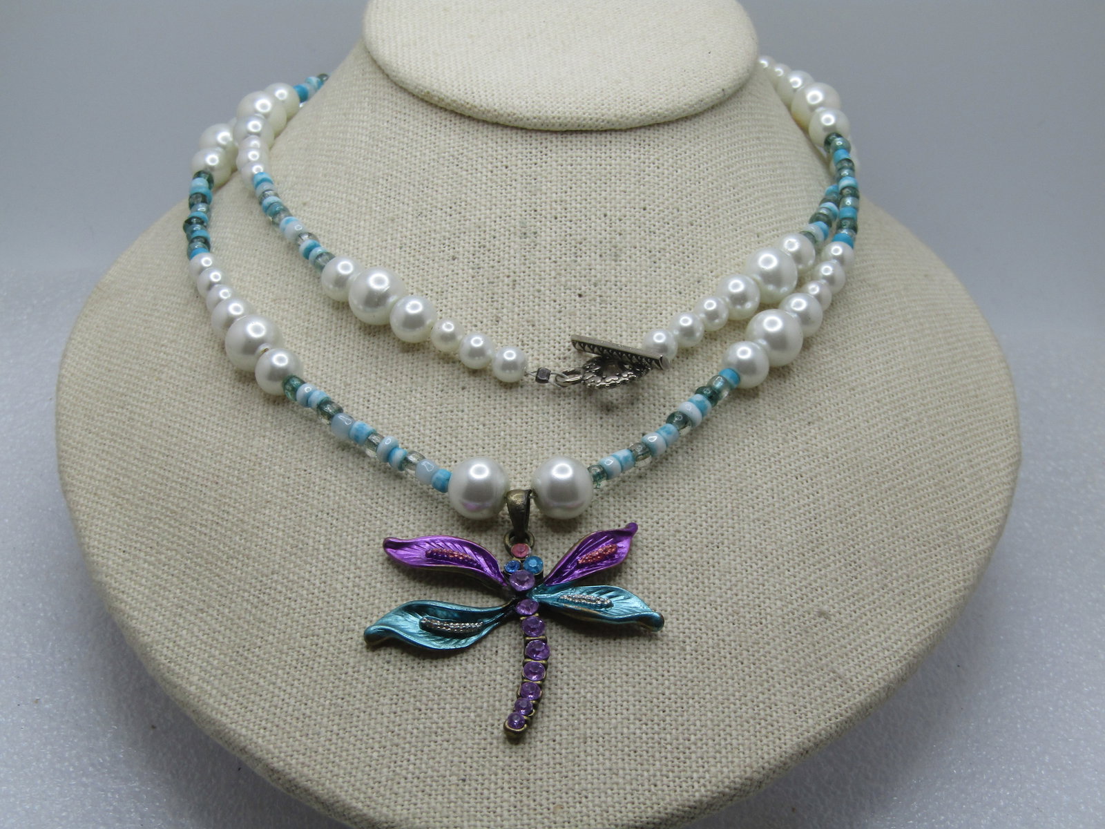Vintage Rhinestone Dragonfly Faux Pearl Necklace, Aqua Glass Beads, 32" Toggle, 1980's-1990's: Vintage Rhinestone Dragonfly Faux Pearl Necklace, Aqua Glass Beads, 32" Toggle, 1980's-1990's. The dragonfly has aqua, pink rhinestones with metallic enameled aqua and ppink wings. The necklace is 32"