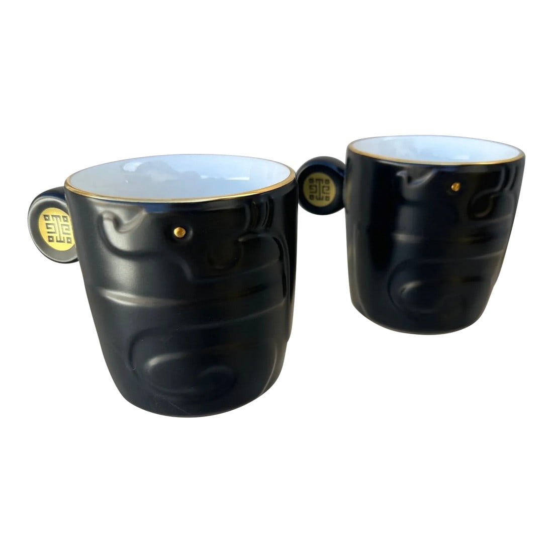 Pair of National Palace Museum Black Mugs: Pair of Dragons Leap to Life Black/Gold Coffee Mugs, unique handles with gold trim and gold pattern on handle. From the National Palace Museum. Discontinued 5in w to handle x 3.5in w x 3.25in h 