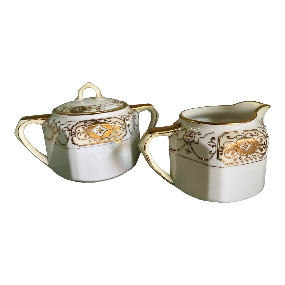 Early 20th Century Hollywood Regency Sugar & Creamer: This sugar and creamer set is white porcelain heavily decorated with gold . The creamer is 2-5/8" tall at the handle and 4-3/4" wide from the spout to the handle. The sugar bowl is 3-1/2" tall and
