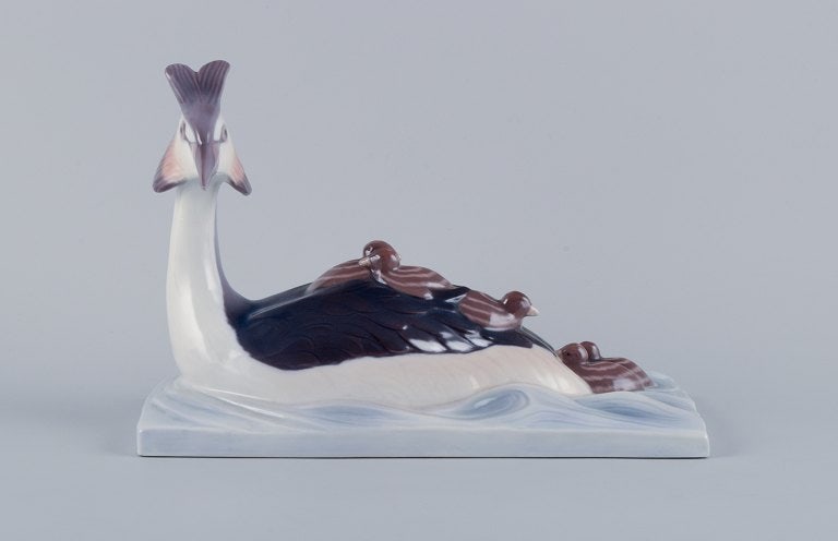 Bing & Grøndahl figurine of a tufted duck with ducklings.: Bing & Grondahl figurine of a tufted duck with ducklings. Model number 2439. First factory quality. In perfect condition. Marked with the manufacturer's mark. Dimensions: L 28,0 cm. x H 19,0 cm. 