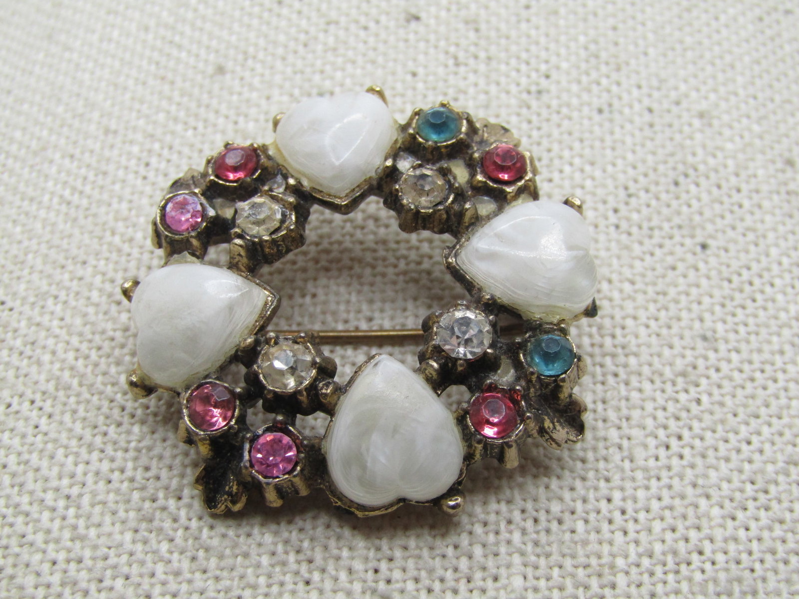 Vintage Rhinestone & Heart Circle Brooch, 1950's-1960's: Vintage Rhinestone & Heart Circle Brooch, 1950's-1960's. Gold tone with four plastic white faux agate hearts with pink, blue, and clear rhinestones. It is appx. 1.25" wide. Good to very good condition