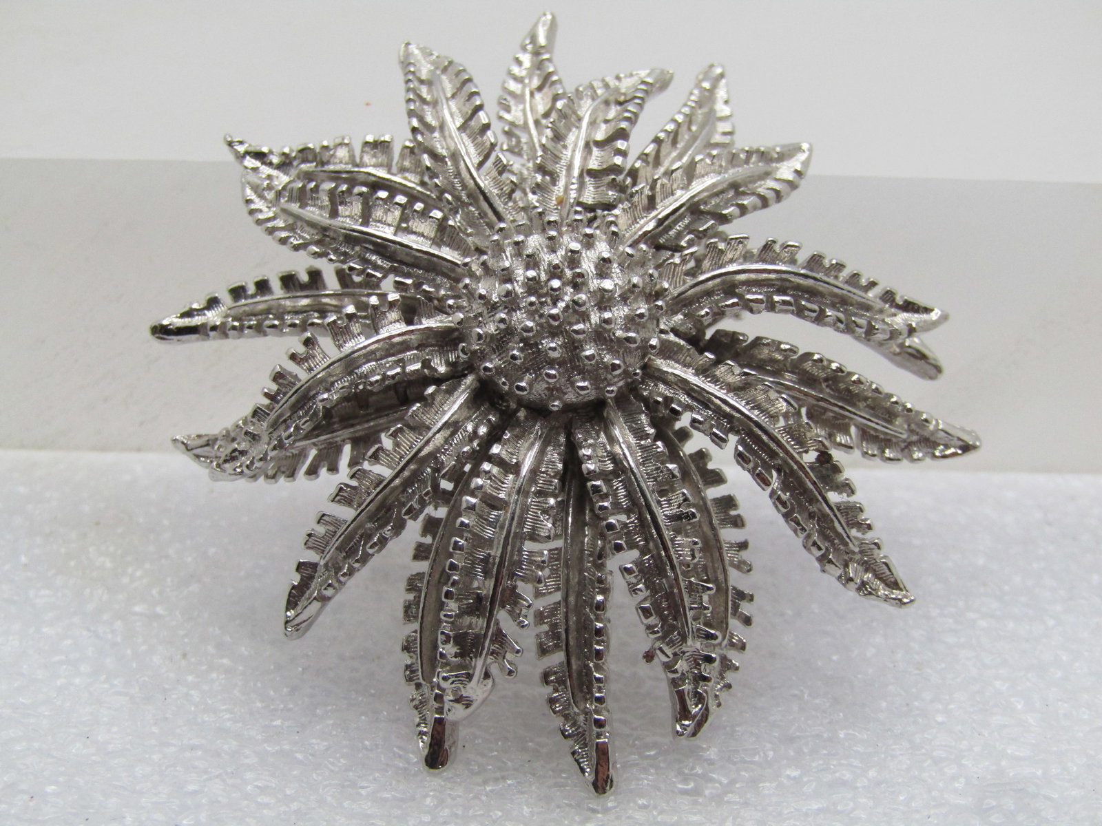 Vintage Coro Blossom Brooch, Tiered, 1960's: Vintage Coro Blossom Brooch, Tiered, 1960's, Silver tone with smooth and textured finish with the fern-like petals reaching downward and a round cetner with raised smooth dots. It is appx. 2" wide. It