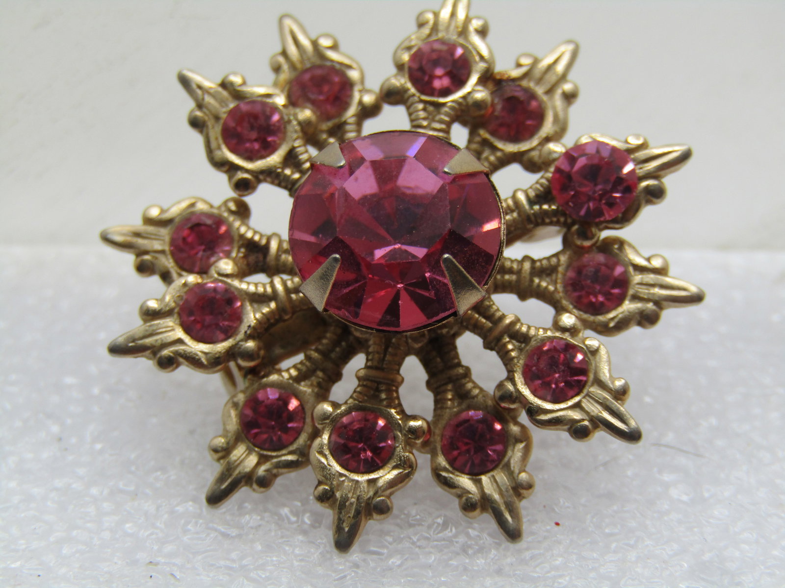 Vintage Pink Rhinestone Snowflake Brooch, 1940's-1960's: Vintage Pink Snowflake Brooch, 1940's-1960's. This has 10mm pink top center rhinestone, pr ong-set with two tiers of tiered snowflake designs that are appx. 2.5mm round. Gold tone. It is appx. 1.25" a