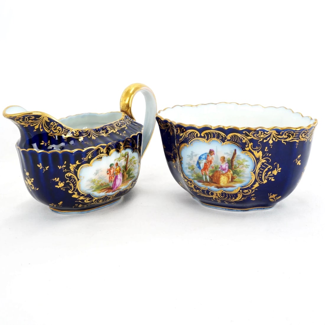 Antique German Dresden Creamer Sugar Set: Title:Antique German Dresden Creamer Sugar Set Size:Creamer – 6 in (15.2 cm) long x 3 in (7.6 cm) wide x 3 3/8 in (8.4 cm) tall Sugar bowl – 5 in (12.7 cm) long x 3 ½ in (8.9 cm) wide x 2